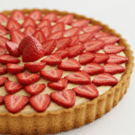 Une magnifique tarte aux fruits (fraises ici) mettant en valeur la texture dorée et friable de la pâte sablée.