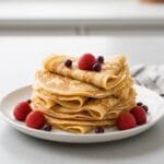 5 étapes pour réussir de Recette pour crêpe facile Pile de crêpes dorées garnies de fruits frais, illustrant une recette pour crêpe facile et réussie.
