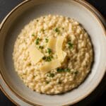 Une assiette élégante de risotto crémeux, parsemé de persil frais et parmesan râpé. Apprenez comment réussir un risotto créme