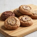 Des cookies aux pépites de chocolat dorés, empilés sur une table en bois, illustrant une recette cookie facile et gourmande.