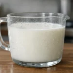 60 cl de lait en gramme, conversion précise, tasse en verre graduée avec lait, cuisine réaliste.