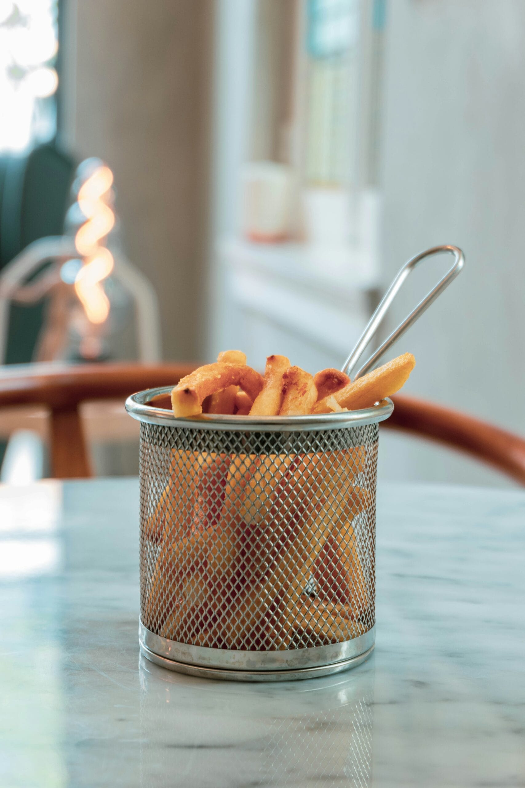Avis Actifry Tefal vs EssentielB: 3 Critères Pour Choisir Ta Friteuse Sans Huile Des frites de patate douce croustillantes dans un panier d'un friteuse à air, montrant la texture et l'assaisonnement de sel.